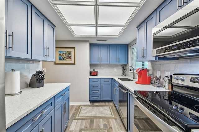 kitchen featuring blue cabinets, sink, light stone counters, light wood-type flooring, and stainless steel appliances