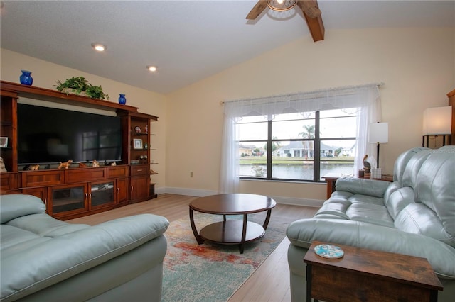 living room with a water view, lofted ceiling with beams, a ceiling fan, and light wood-style floors