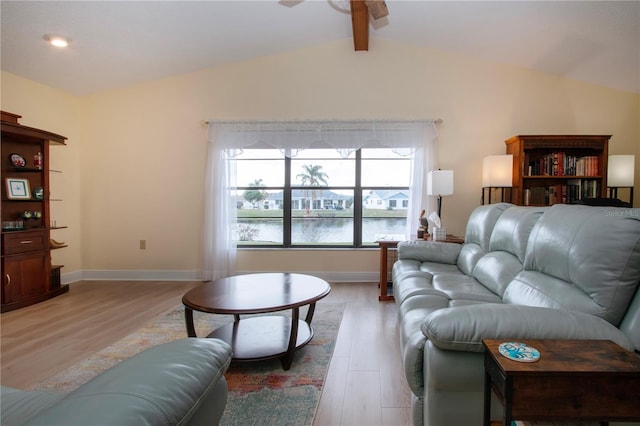 living room with light wood finished floors, a water view, a ceiling fan, and vaulted ceiling with beams