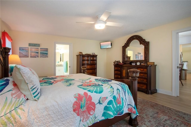 bedroom with ensuite bathroom, wood finished floors, visible vents, a ceiling fan, and baseboards