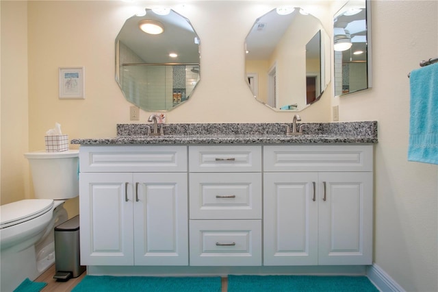 bathroom featuring double vanity, toilet, and a sink