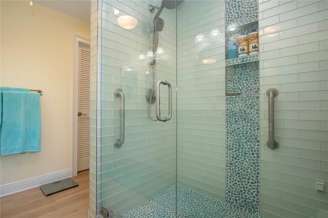 full bath featuring a shower stall, baseboards, and wood finished floors