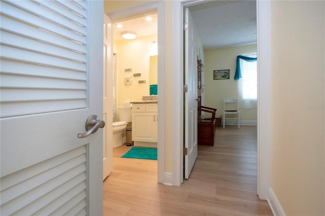 hallway featuring light wood-style flooring and baseboards