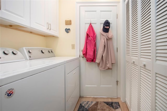 washroom featuring washing machine and clothes dryer, cabinet space, and light wood-style floors