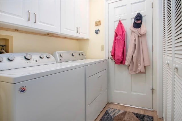 laundry area featuring washing machine and dryer, light wood-style flooring, and cabinet space