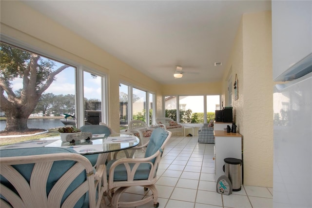 sunroom / solarium featuring a water view, tile patterned flooring, and visible vents