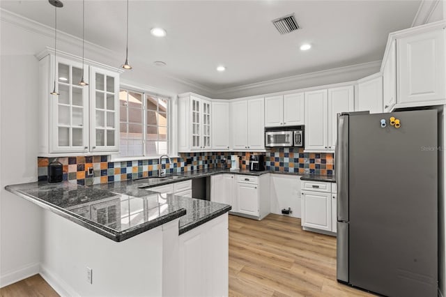 kitchen with appliances with stainless steel finishes, sink, white cabinets, hanging light fixtures, and kitchen peninsula