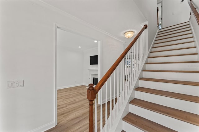 stairway featuring ornamental molding and wood-type flooring