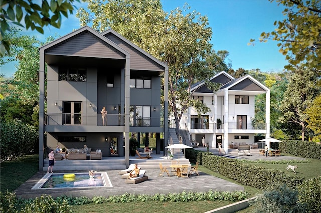 rear view of house with a patio, a balcony, and an outdoor living space with a fire pit