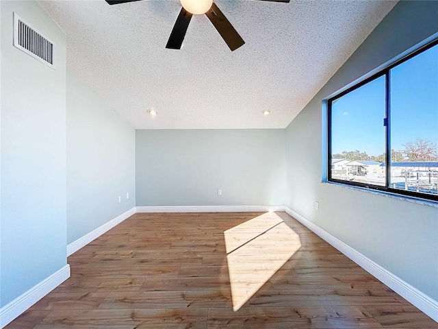 unfurnished room with ceiling fan, lofted ceiling, hardwood / wood-style floors, and a textured ceiling