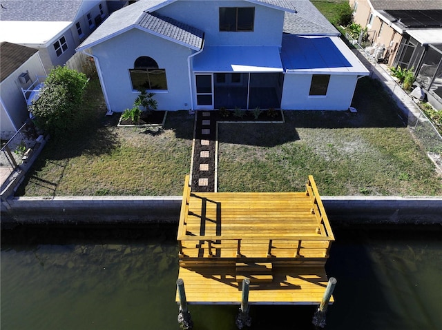 back of property featuring a water view and a lawn