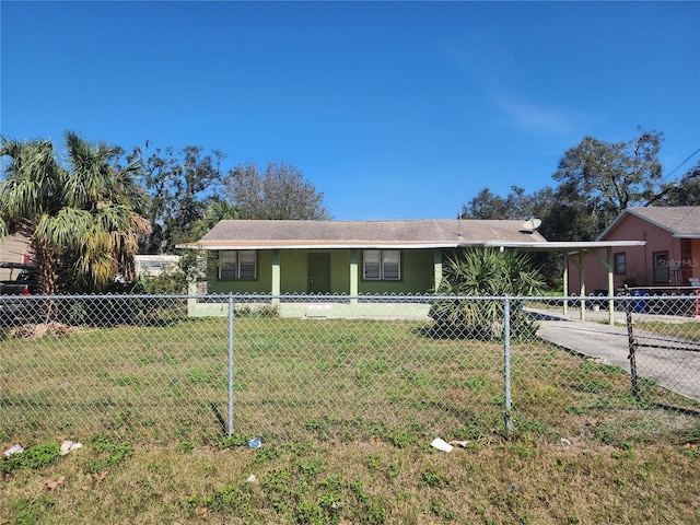 view of front facade with concrete driveway, an attached carport, fence, a front yard, and stucco siding