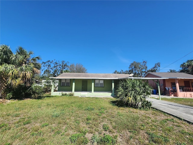 single story home featuring driveway, an attached carport, a front yard, and stucco siding