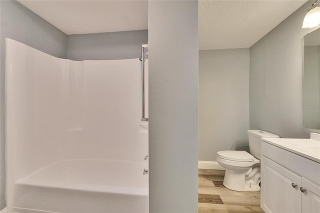 bathroom with a textured ceiling, toilet, wood finished floors, vanity, and shower / bathing tub combination