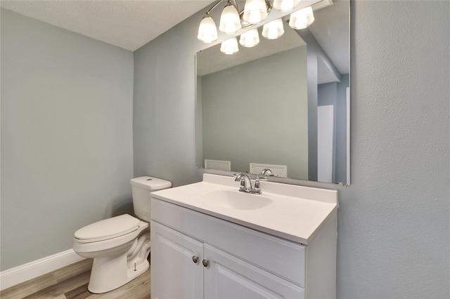 half bathroom featuring toilet, baseboards, wood finished floors, and vanity