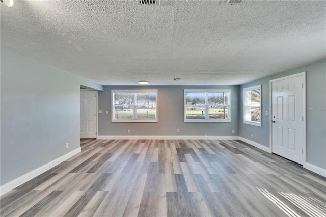 unfurnished living room featuring plenty of natural light, baseboards, and wood finished floors