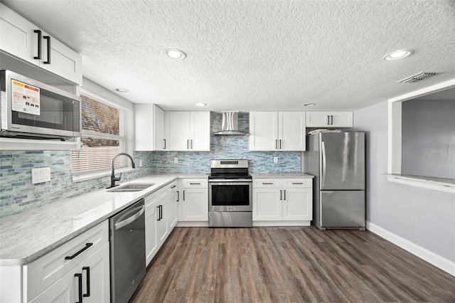 kitchen with wall chimney exhaust hood, white cabinetry, appliances with stainless steel finishes, and sink