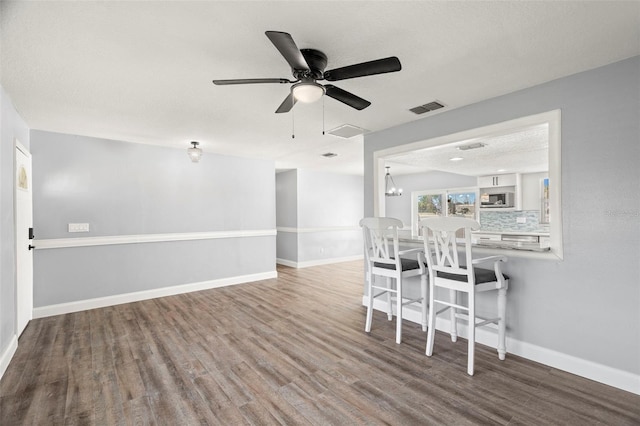 unfurnished dining area with hardwood / wood-style flooring, ceiling fan with notable chandelier, and a textured ceiling