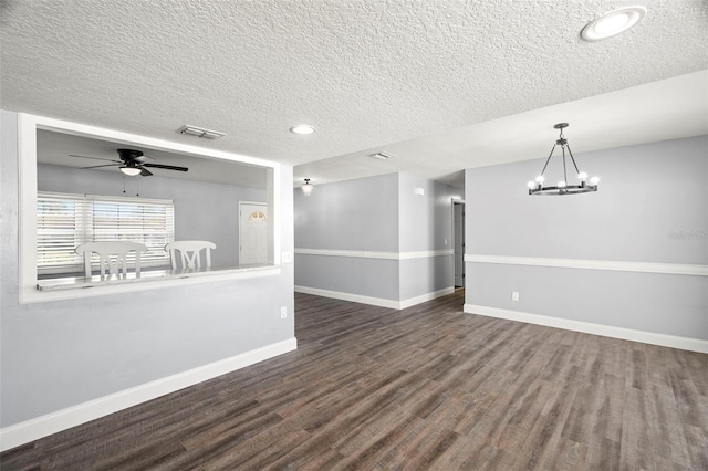 empty room featuring dark wood-type flooring, ceiling fan with notable chandelier, and a textured ceiling