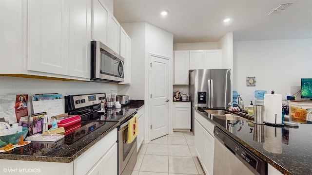 kitchen featuring white cabinetry, stainless steel appliances, dark stone countertops, and light tile patterned flooring