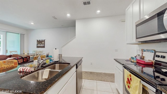 kitchen with light tile patterned flooring, sink, white cabinetry, appliances with stainless steel finishes, and dark stone counters