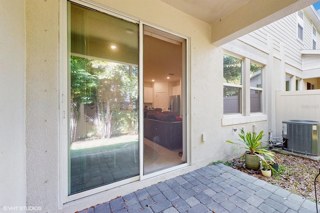 view of exterior entry with a patio area and central air condition unit