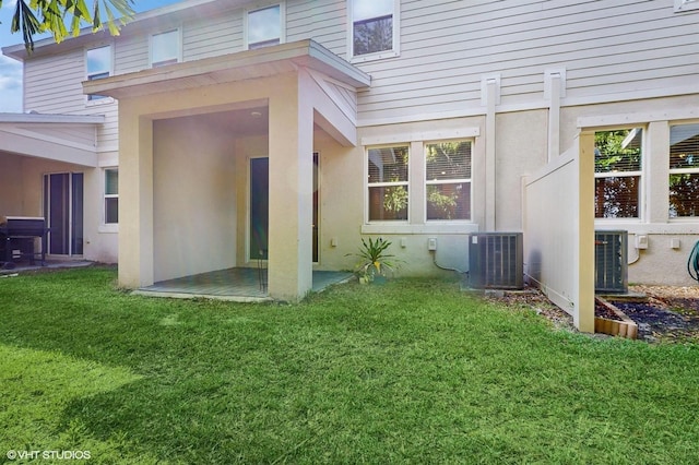 rear view of house featuring central AC unit and a lawn