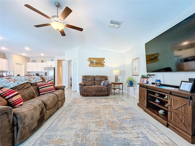 living room featuring ceiling fan, lofted ceiling, a textured ceiling, and light tile patterned floors