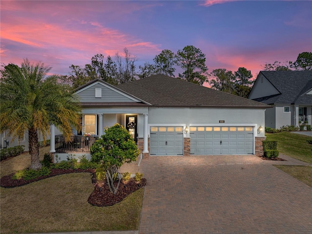 view of front of property featuring a garage, a lawn, and a porch