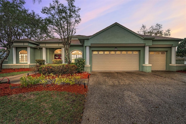 view of front facade featuring a garage, driveway, and stucco siding