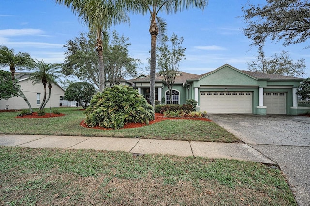 view of front of home with driveway, a front yard, an attached garage, and stucco siding