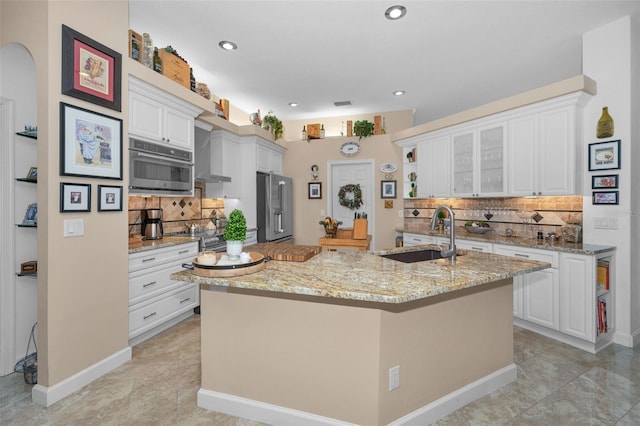 kitchen with high quality fridge, white cabinetry, a sink, and light stone counters