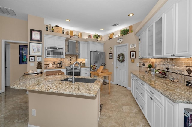 kitchen featuring light stone counters, stainless steel appliances, visible vents, white cabinetry, and a sink