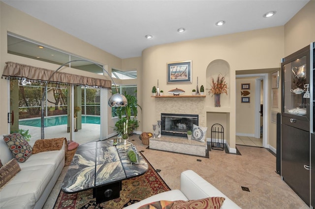 living area with baseboards, a tile fireplace, and recessed lighting