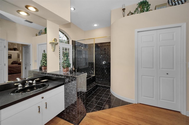 bathroom with recessed lighting, visible vents, a tile shower, vanity, and wood finished floors