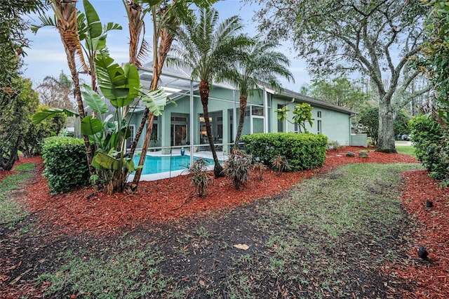 rear view of house featuring stucco siding, a lanai, and an outdoor pool