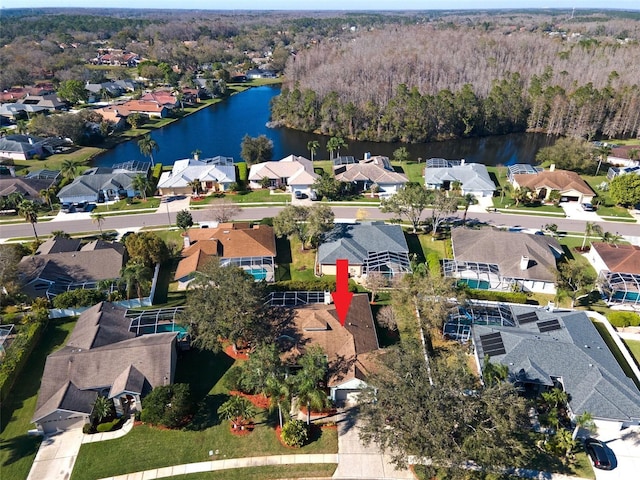 drone / aerial view with a residential view, a water view, and a view of trees