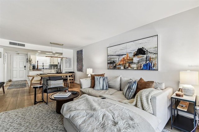 living area featuring visible vents and wood finished floors