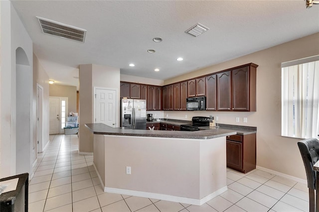 kitchen featuring light tile patterned flooring, dark brown cabinets, a center island, and black appliances