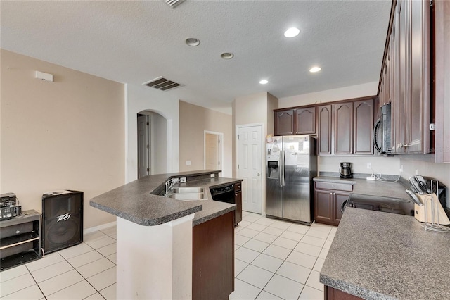 kitchen with light tile patterned flooring, dark brown cabinetry, sink, appliances with stainless steel finishes, and a kitchen island with sink