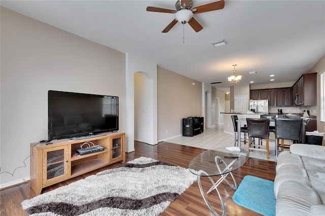 living room with ceiling fan with notable chandelier and light wood-type flooring