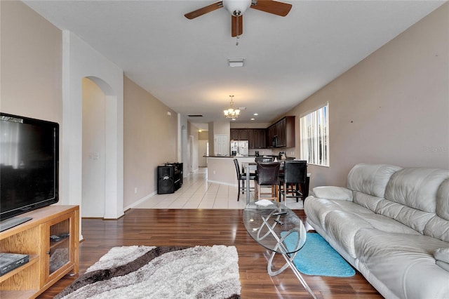 living room featuring ceiling fan with notable chandelier and light wood-type flooring