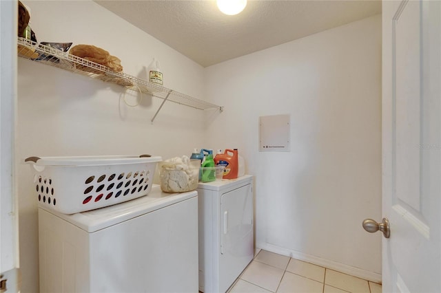 laundry room featuring light tile patterned floors, independent washer and dryer, and a textured ceiling