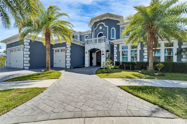 view of front of house featuring a garage, decorative driveway, a front lawn, and stucco siding