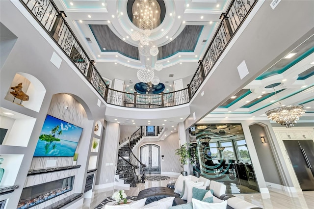 interior space with a glass covered fireplace, stairway, ornamental molding, marble finish floor, and a notable chandelier