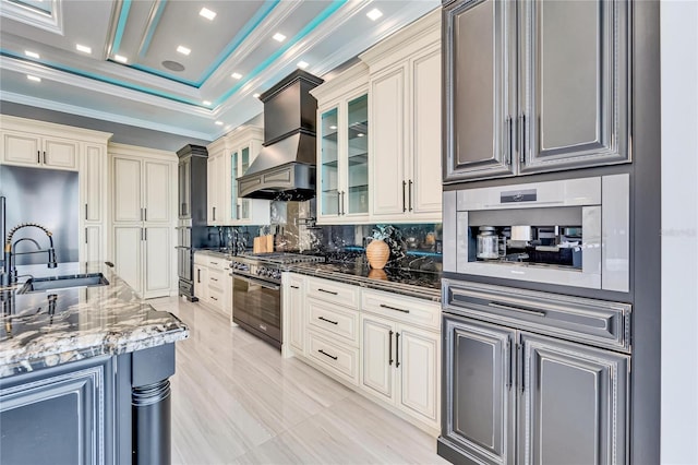 kitchen with a sink, decorative backsplash, dark stone counters, range with gas cooktop, and crown molding