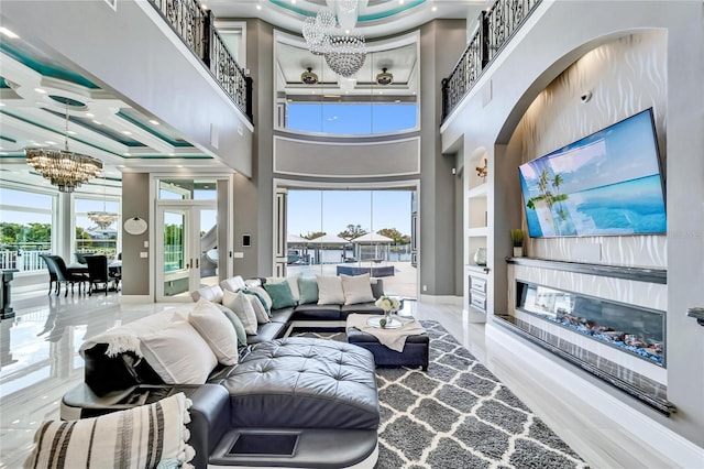 living room with plenty of natural light, built in shelves, a chandelier, and a glass covered fireplace