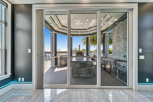 doorway with a tray ceiling, floor to ceiling windows, and baseboards