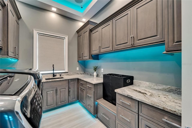 laundry room with light wood-style floors, washer and dryer, cabinet space, and a sink