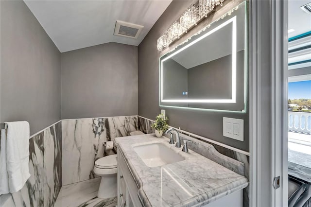 half bath with lofted ceiling, toilet, visible vents, vanity, and marble finish floor